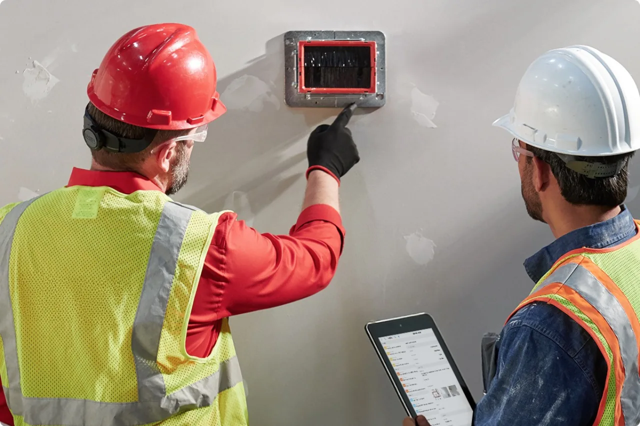 Inspector checking a firestop seal around cable penetrations with a tablet in Saudi Arabia